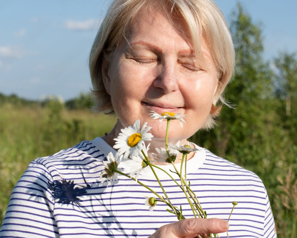 Beautiful happy menopause woman in a meadow with flowers. 