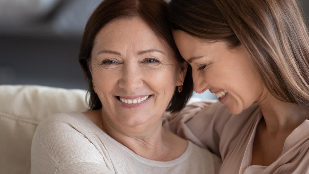 Close up smiling mature mother and daughter hugging, touching heads, expressing love and care, young woman and middle aged mum enjoying tender moment