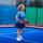 Middle age woman playing padel on outdoor court.